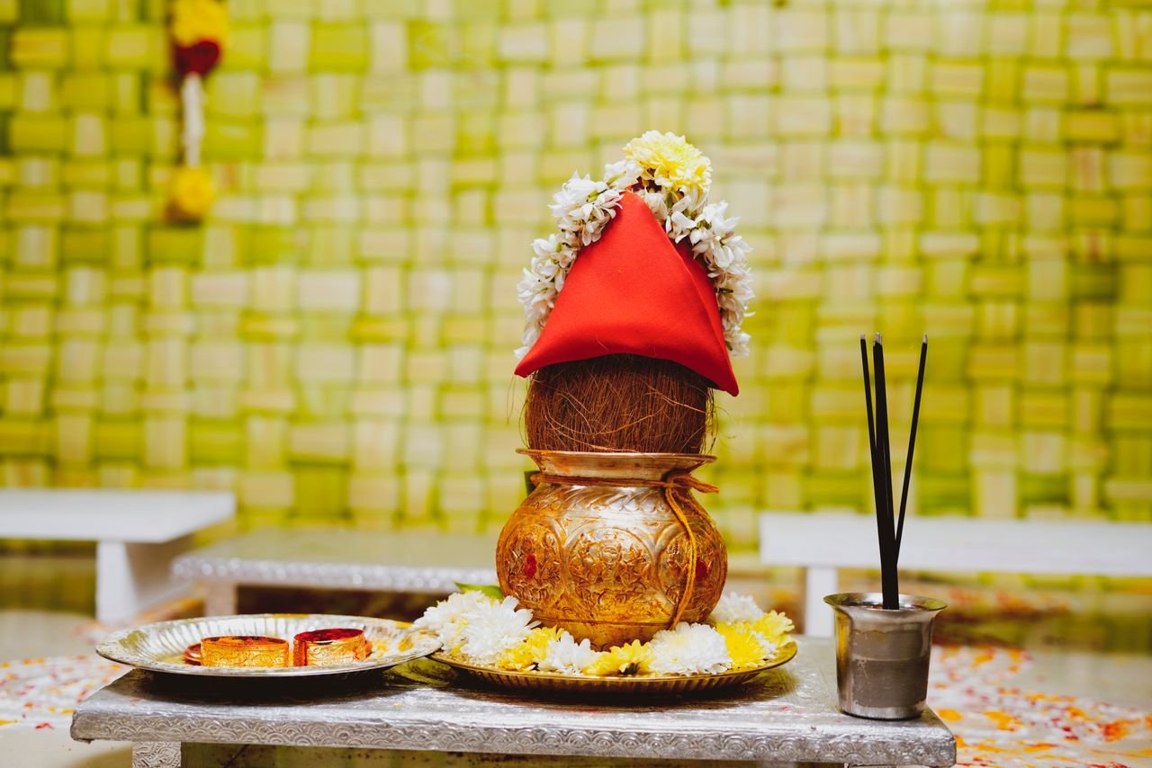 Vibrant traditional Indian Kalash with floral decorations for ceremonial rituals on a decorated table.