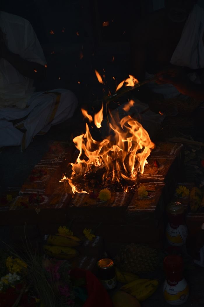A vibrant fire ritual with offerings and participants in traditional attire, captured in Thoothai, TN, India.