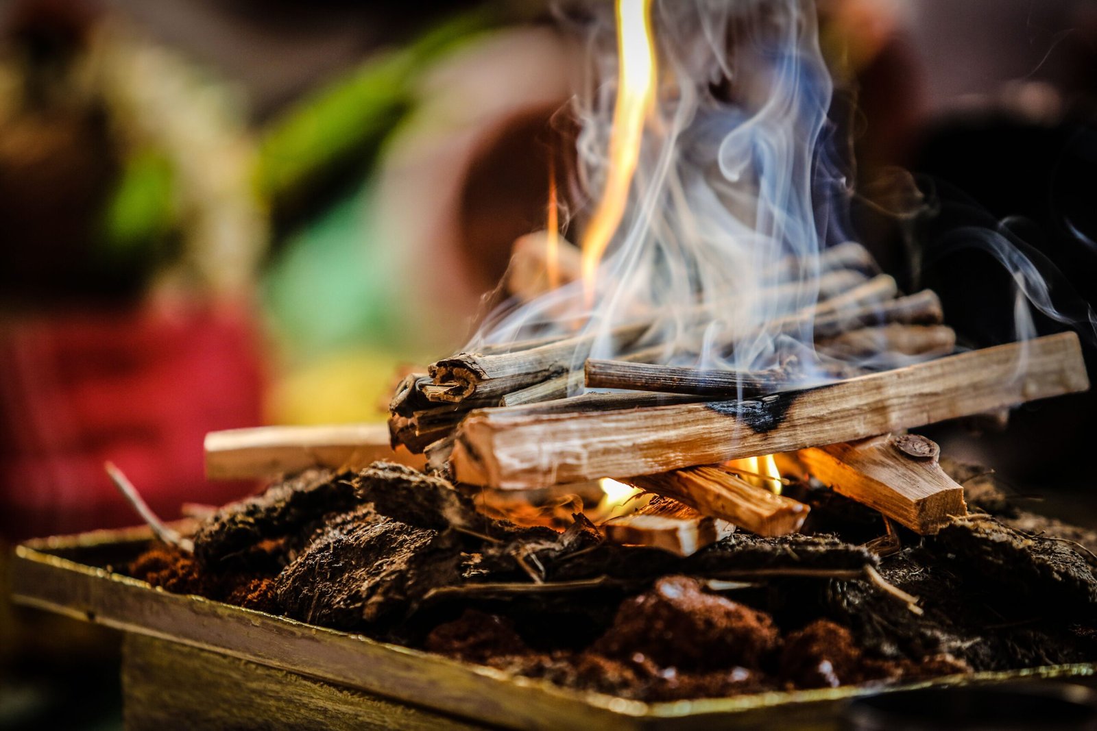 A detailed close-up of firewood burning with smoke rising, creating a warm and vibrant visual.